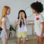 Cheerful multiethnic children in casual clothes playing hide and seek while spending weekends together