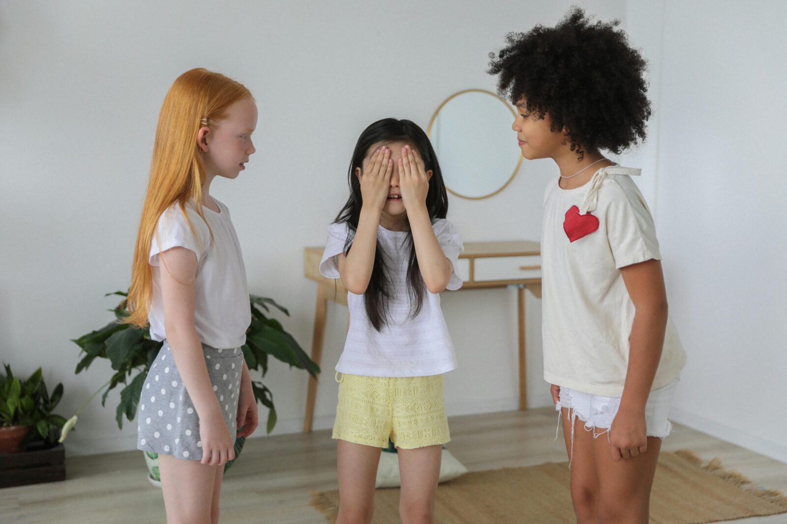 Cheerful multiethnic children in casual clothes playing hide and seek while spending weekends together