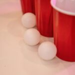 Close-up of red cups and ping pong balls on a white surface, ideal for party themes.