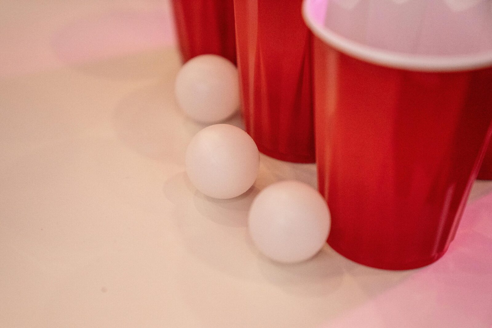 Close-up of red cups and ping pong balls on a white surface, ideal for party themes.