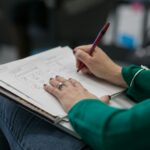 person writing on paper at lap
